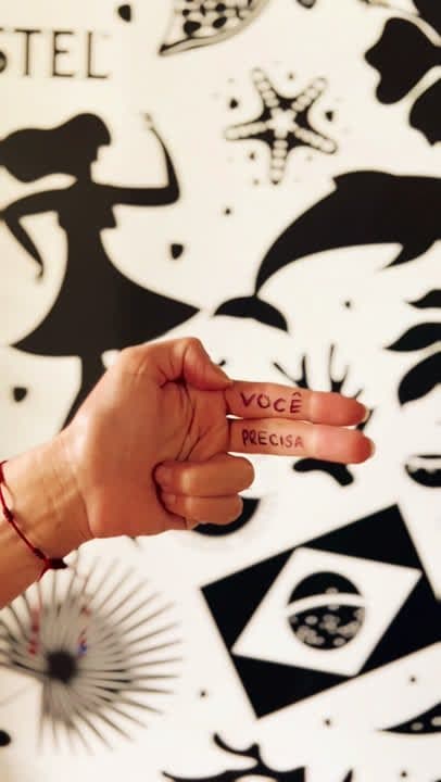 Foto de mão segurando uma peça em frente a uma parede ilustrada em preto e branco.